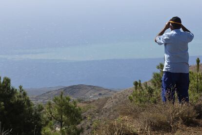 Un hombre observa la mancha volcánica con unos prismáticos desde el municipio de El Pinar.
