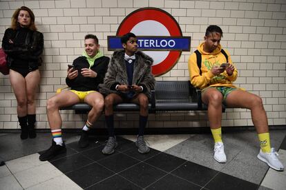 Las personas se sientan a esperar un tren en la estación de metro de Waterloo, situada en el centro de Londres, mientras participan en el 'Día sin pantalones en el metro', el 12 de enero.