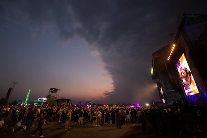 Asistentes se congregan frente a un escenario antes del comienzo de un concierto.