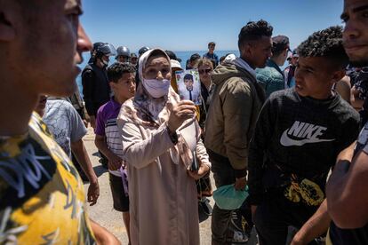 A woman shows a photo of her child to migrants on a beach in Fnideq.