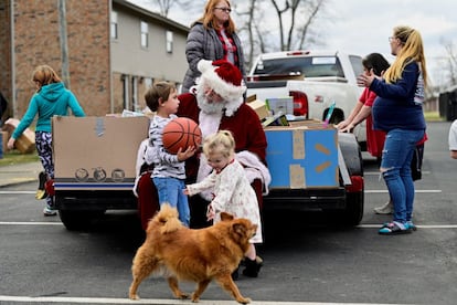 Troy Black, vestido como Papá Noel, entrega juguetes a varios niños en un vecindario devastado por los tornados en Dawson Springs, Kentucky, el 24 de diciembre.