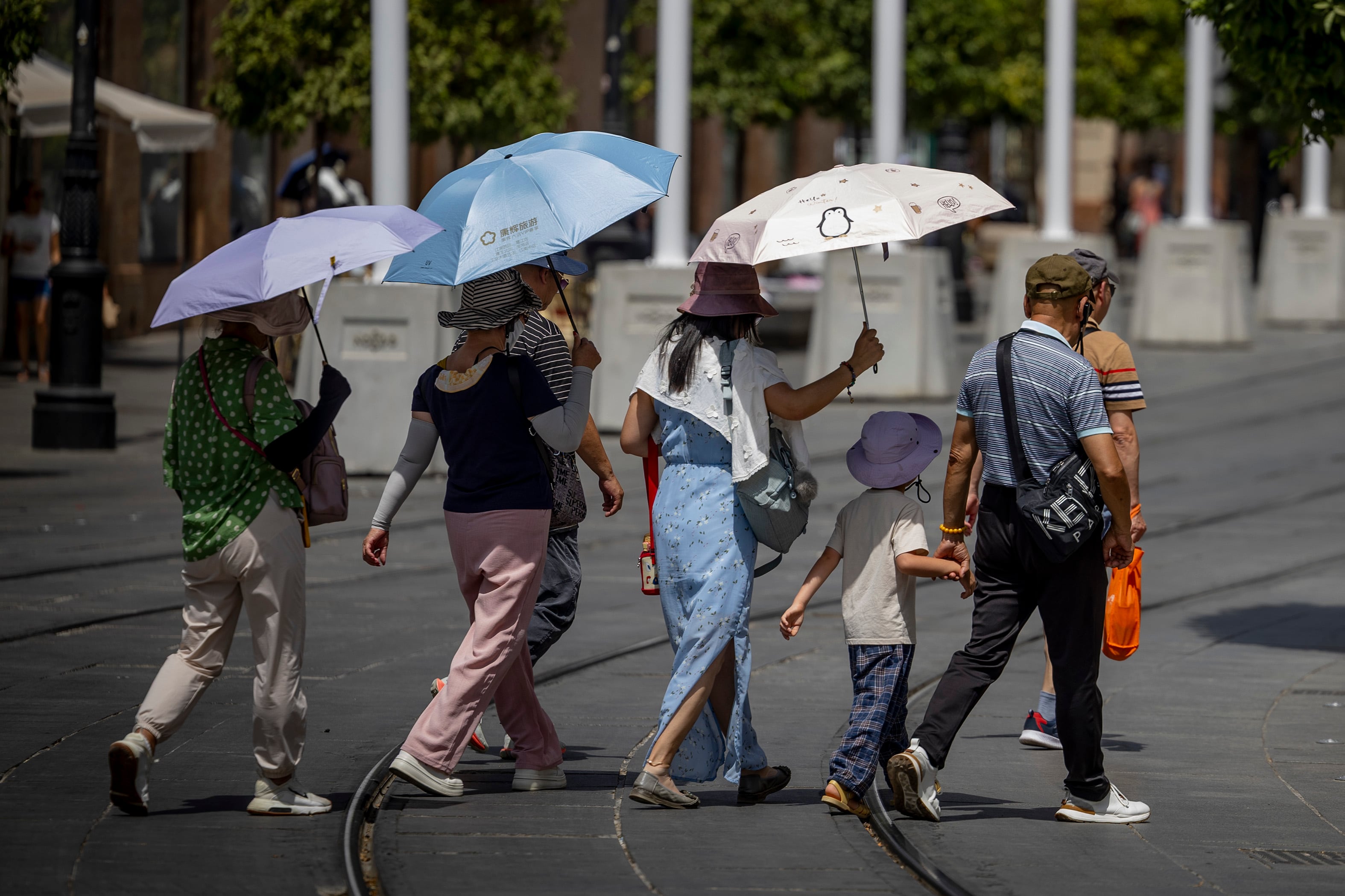 Unos turistas se protegen con paraguas del sol, el sábado en Sevilla.