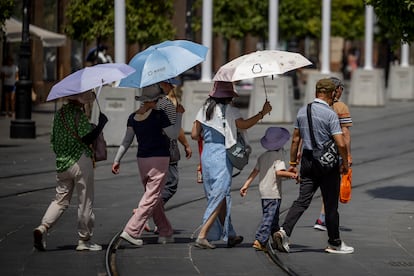 Unos turistas se protegen con paraguas del sol, el sábado en Sevilla.