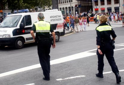 Dos agentes de la Policía Municipal de Bilbao patrullan junto a una unidad de atestados, en el Arenal.