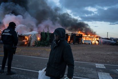 Un migrante pasa delante de una chabola incendiada antes de la demolición del asentamiento, este lunes en Níjar. A las ocho de la mañana, coincidiendo con el inicio del desalojo, un incendio ha arrasado varias chabolas. Los bomberos sofocaron las llamas con rapidez, pero el fuego facilitó el desalojo del recinto a las fuerzas de seguridad, que sostenían que había sido iniciado por los propios habitantes del asentamiento. 