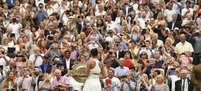 Muguruza exhibe el trofeo de campeona al público de la central.