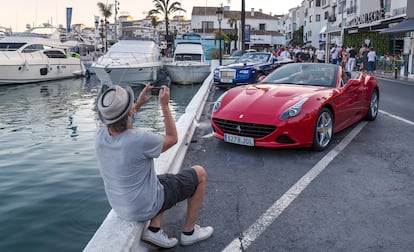 Un hombre fotografía un Ferrari en Puerto Banús, Málaga.