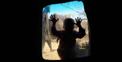 Un niño afgano desplazado internamente mira desde una ventana en su hogar temporal (Afganistán).