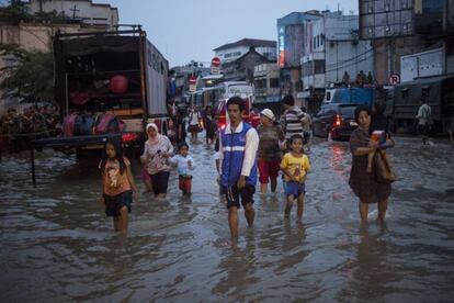 Pessoas de Jacarta caminham por uma rua inundada.