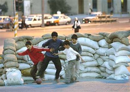 Niños iraquíes juegan al fútbol en una barricada construida con sacos terreros en Bagdad.