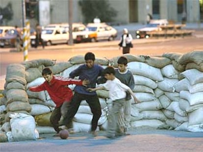 Niños iraquíes juegan al fútbol en una barricada construida con sacos terreros en Bagdad.