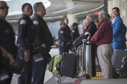 Agentes de policía y viajeros en la salida de un aeropuerto.