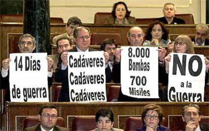 Los diputados de IU exhiben pancartas contrarias a la guerra durante el pleno.