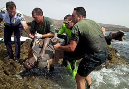 Agentes de la Guardia Civil sacan del mar el cuerpo de uno de los 10 inmigrantes ahogados ayer al chocar su patera contra las rocas en Fuerteventura.