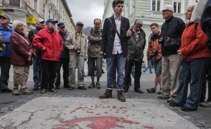 Un grupo de turistas antes una de las llamadas rosas de Sarajevo.