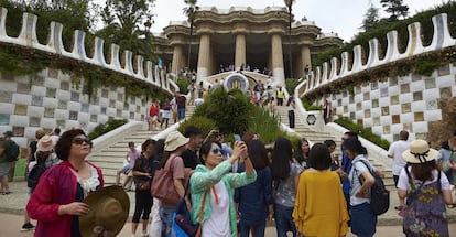 Numerosos turistas pasean por la zona monumental del parque Güell de Barcelona