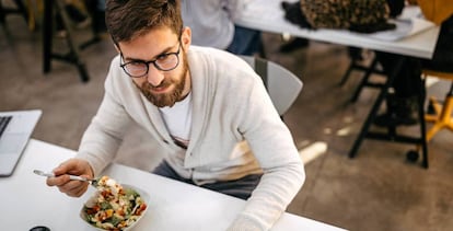 Un trabajador comiendo en su empresa. Getty