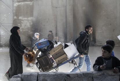 Un hombre tira de un carro mientras una mujer camina detrs cerca del control de Bustan al-Qasr, que est bajo control de los rebeldes en Alepo (Siria).