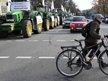 Un hombre cruza una carretera con su bicicleta cerca de una línea de tractores que bloquea el parlamento en Kiev el 12 de noviembre de 2019