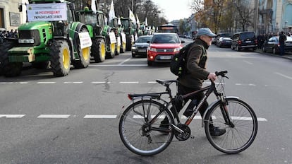 Un hombre cruza una carretera con su bicicleta cerca de una línea de tractores que bloquea el parlamento en Kiev el 12 de noviembre de 2019