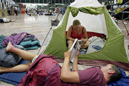 Una pareja descansa en una tienda de campaña que montó en la terminal del aeropuerto.