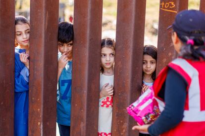 Niños migrantes de Afganistán esperan recibir unos dulces entre las vallas fronterizas de entre México y Estados Unidos en San Diego, California, en septiembre de 2023.