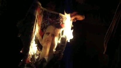 Un hombre quema un retrato de Bachar El Asad.