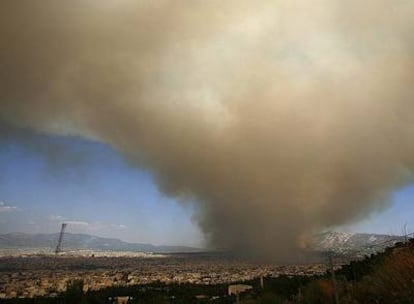 Una nube de humo provocada por el incendio sobre la montaña Pendelis se extiende ayer sobre Atenas.