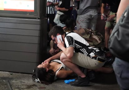 Un hombre atiende a una mujer herida durante la estampida en la plaza de San Carlo, en Tur&iacute;n, el s&aacute;bado