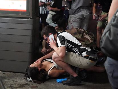 Un hombre atiende a una mujer herida durante la estampida en la plaza de San Carlo, en Tur&iacute;n, el s&aacute;bado