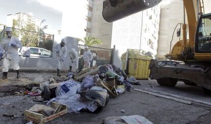 Trabajadores de los servicios m&iacute;nimos y una retroexcavadora de Tragsa trabajan en la recogida de basura.