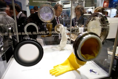 FILE PHOTO: Visitors look at protective gloves by equipment manufacturer Getinge La Calhene displayed at the World Nuclear Exhibition 2014, the trade fair event for the global nuclear energy sector, in Le Bourget, near Paris