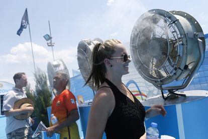 Asistentes a un torneo deportivo se refrescan frente a unos ventiladores.