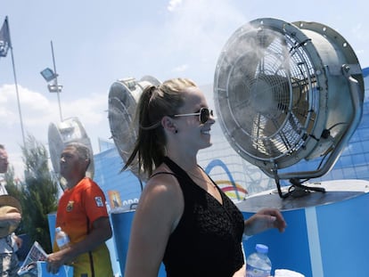 Asistentes a un torneo deportivo se refrescan frente a unos ventiladores.