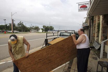 Dos hombres transportan un panel de madera para proteger un edificio de Gulfport (Misisipi), ante la llegada de huracán Isaac.