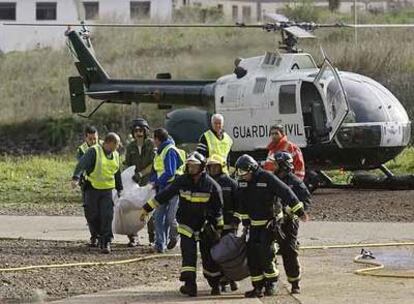 Agentes de la Guardia Civil y bomberos trasladan los cuerpos de los fallecidos en la galería.