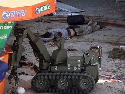 Un robot israelí inspecciona la zona del atentado de ayer en Dimona, al sur de Israel. Al fondo, el cadáver de uno de los terroristas.