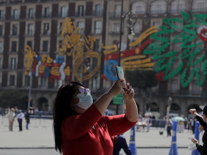 Una mujer toma una fotografía con su teléfono celular frente a la Catedral Metropolitana en el Zócalo de la Ciudad de México.