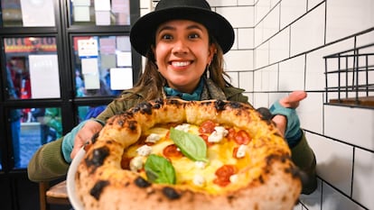 Mariel Galán sostiene una pizza en un restaurante de Roma.  
