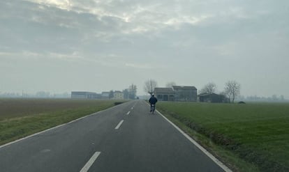 Un agricultor circula en bicicleta poro una carretera cercana a Parma.