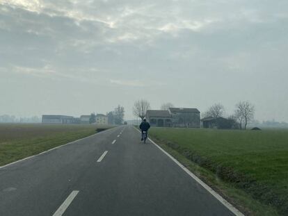 Un agricultor circula en bicicleta poro una carretera cercana a Parma.