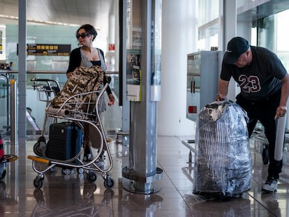 Un embalador se afana a proteger con plástico una maleta, este jueves en el aeropuerto de El Prat.