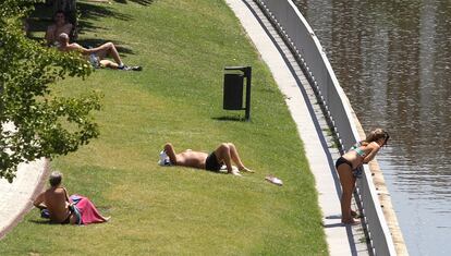 Varias personas toman el sol en la zona de Madrid Rio.