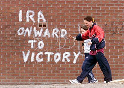 Dos muchachas de Belfast pasan junto a una pintada que dice &#39;El IRA, hacia la victoria&#39;.