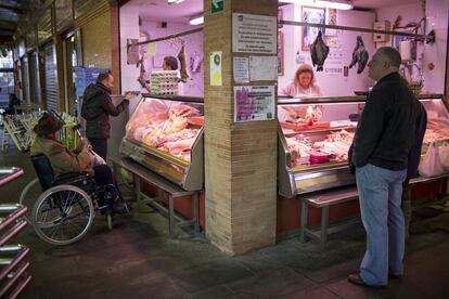 Varias personas compran en un puesto del mercado de Triana, en Sevilla.