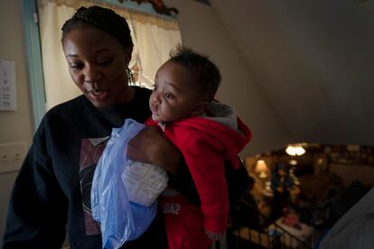 Ansonia Lyons carries her son, Adrien Lyons