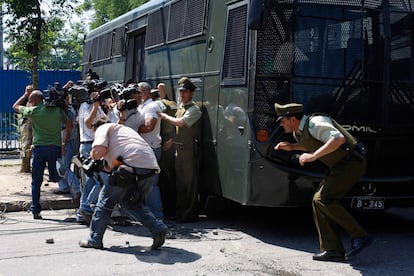 Policías y reporteros se refugian detrás de un furgón policial de las protestas de los familiares de los reclusos de la prisión de San Miguel.