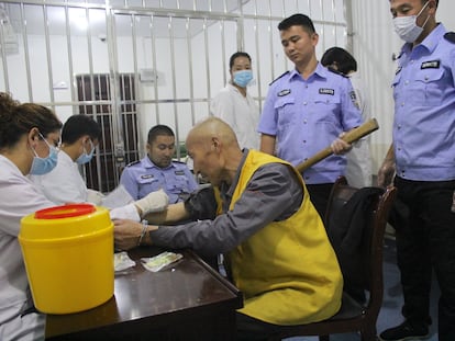 Un hombre esposado y vigilado por policías armados recibe una inyección en un centro de reeducación en Tekes (Xinjiang, China)