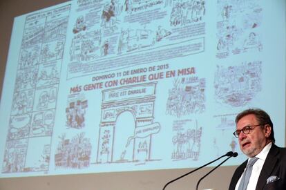 El presidente de PRISA, Juan Luis Cebrián, durante su intervención en el homenaje a las víctimas de 'Charlie Hebdo', con una proyección de las viñetas de la revista satírica francesa de fondo.