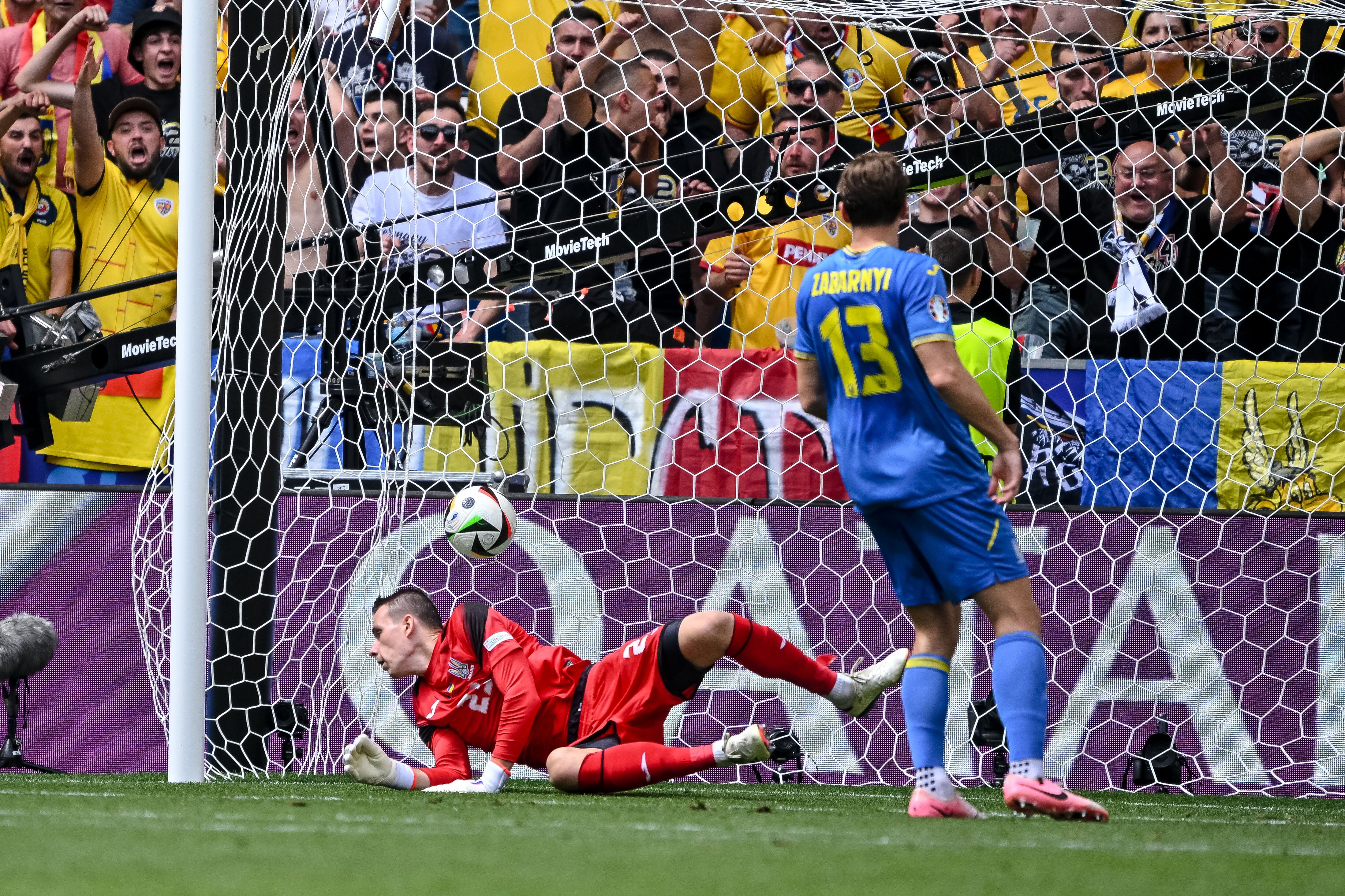 Los ucranios Andrei Lunin e Illia Zabarnyi observan el balón entrar en segundo gol de Rumanía. 